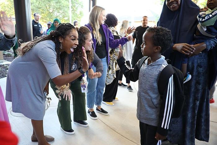 a child high-fives an adult with other adults around them